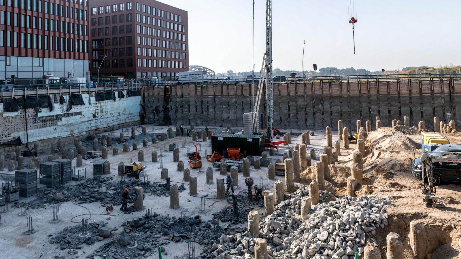 A bustling urban construction site with workers and heavy machinery near tall buildings